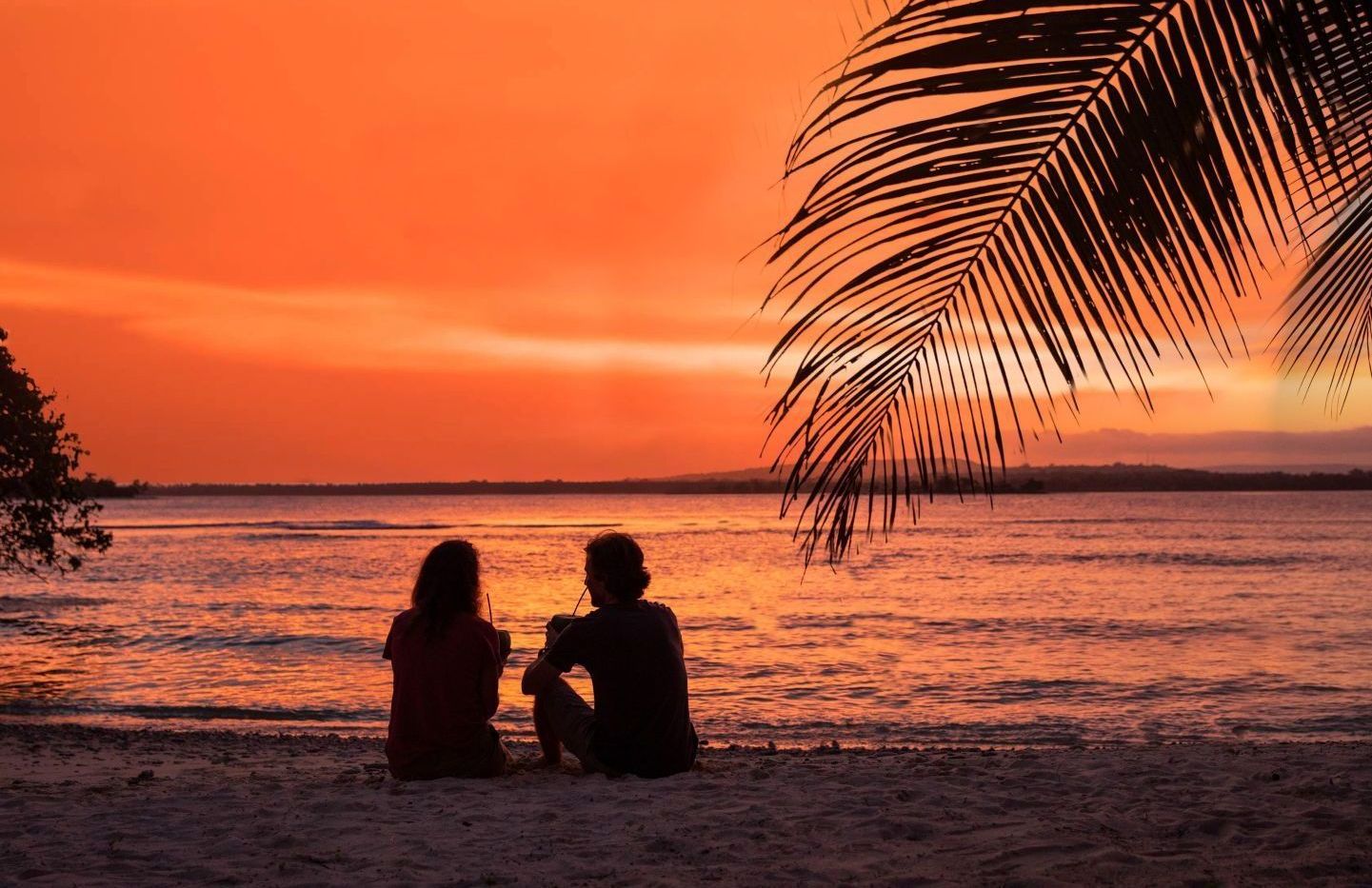 Couple drinking cocktails on a beach at sunset in Tanna
